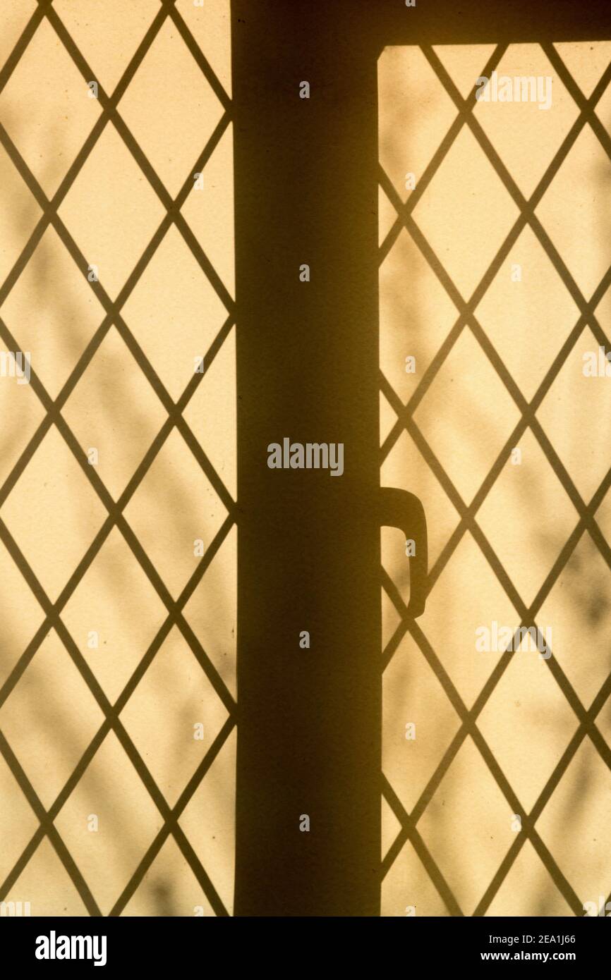Soleil brillant à travers une fenêtre au plomb formant une silhouette sur un store en tissu dans un chalet. Banque D'Images