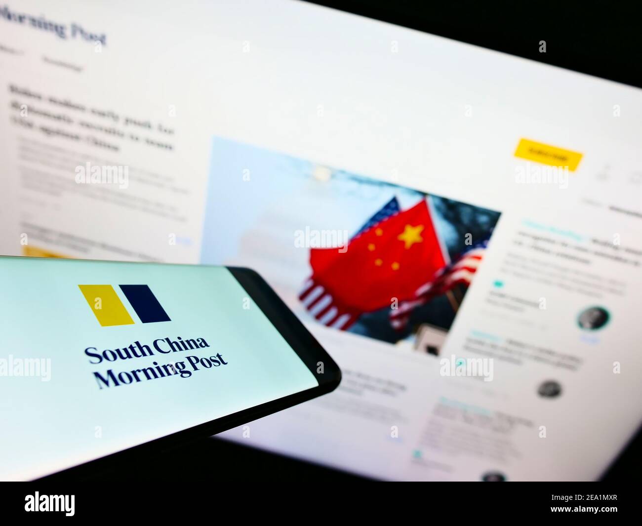 Smartphone avec logo du journal South China Morning Post (Hongkong) sur l'écran en face de la page Web de l'entreprise. Effectuez la mise au point au centre-droit de l'écran du téléphone. Banque D'Images