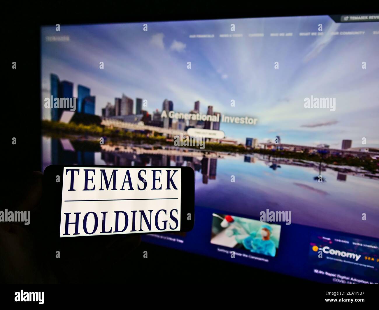 Personne tenant un smartphone avec le logo de la société d'investissement Singapourienne Temasek Holdings sur l'écran devant le site Web. Mise au point sur l'affichage du téléphone. Banque D'Images