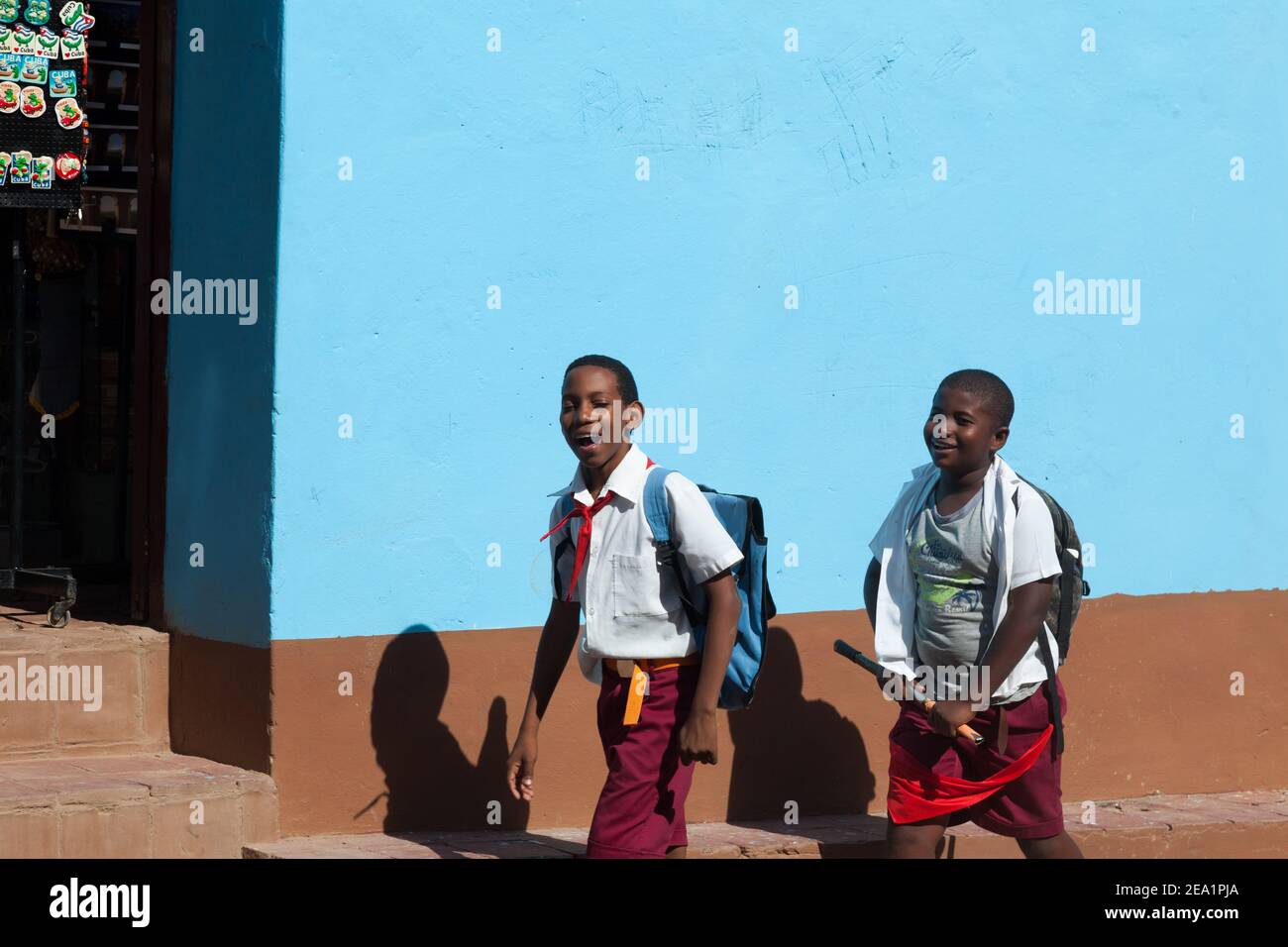 Deux collégiens à pied sur th Street à Cuba Trinidad. Smiling boys sur fond bleu mur. Les enfants ont des pionniers rouge. Banque D'Images