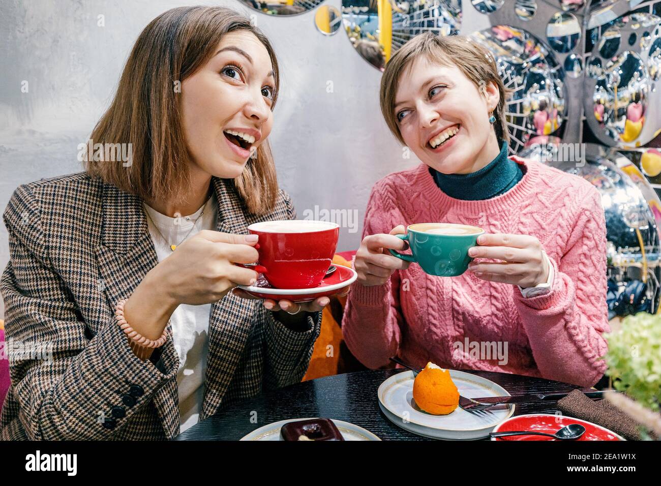 Des filles drôles amis boivent du café dans un café et bavardez et des potins sur les relations Banque D'Images