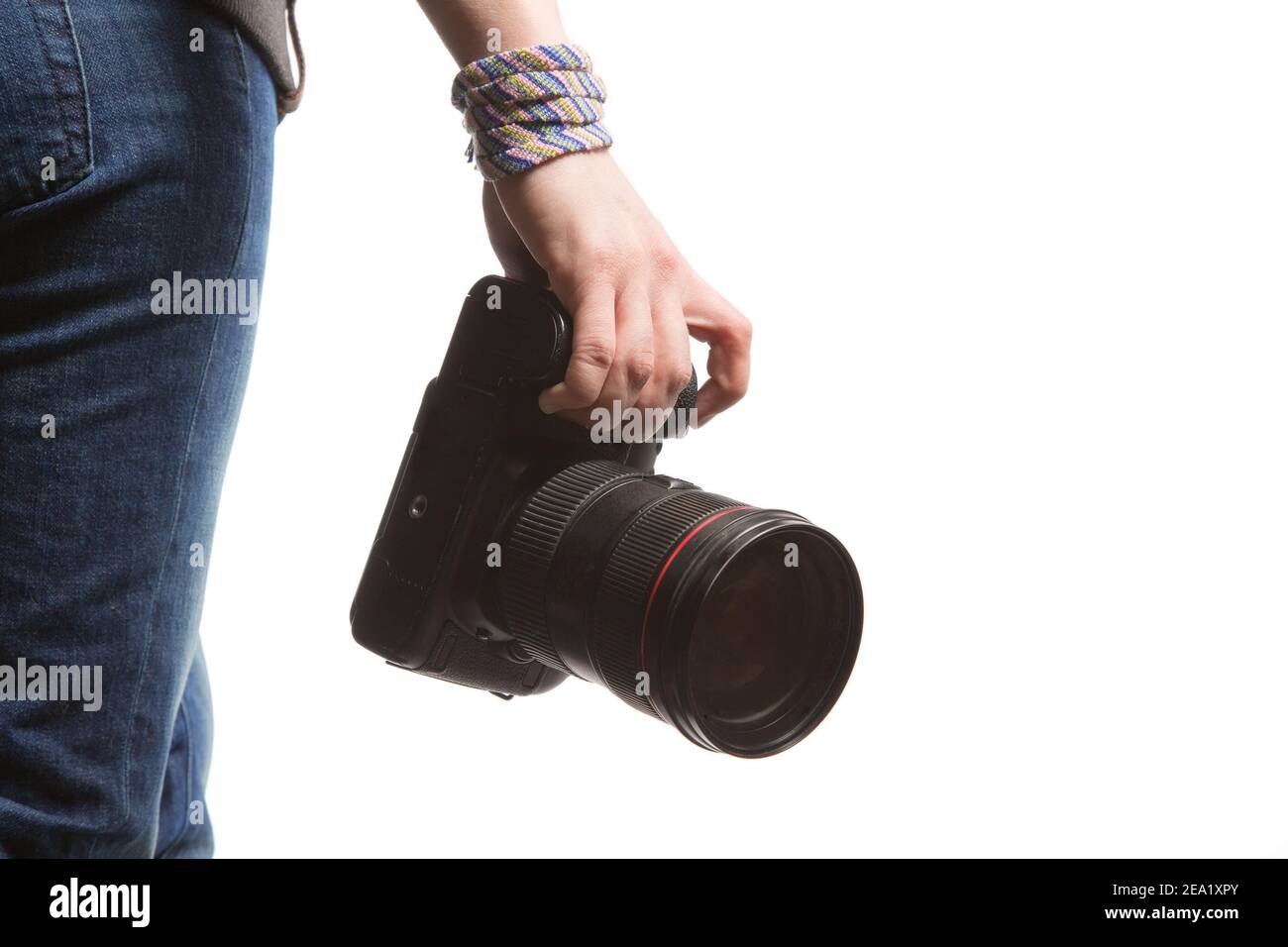 Une femme tient à la main un appareil photo reflex numérique. Isolé sur fond blanc. Vue arrière en studio. Sur le Jean, le sweat-shirt et le bracelet de la fille Banque D'Images
