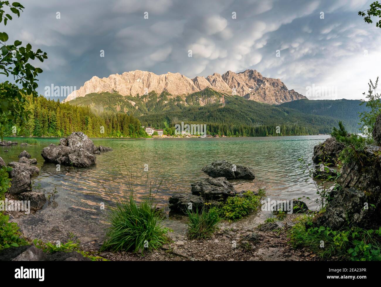 Rochers sur la rive, lac Eibsee en face du massif de Zugspitze avec Zugspitze, nuages spectaculaires de Mammaten, domaine de Wetterstein, près de Grainau, supérieur Banque D'Images