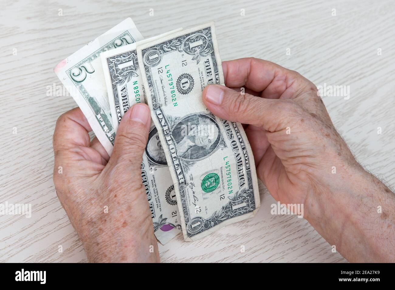 Les mains d'une femme âgée détiennent 1 et 5 dollars. Le concept du désespoir, de la pauvreté, du manque d'argent pour les choses de base et de l'assurance du miel. Banque D'Images