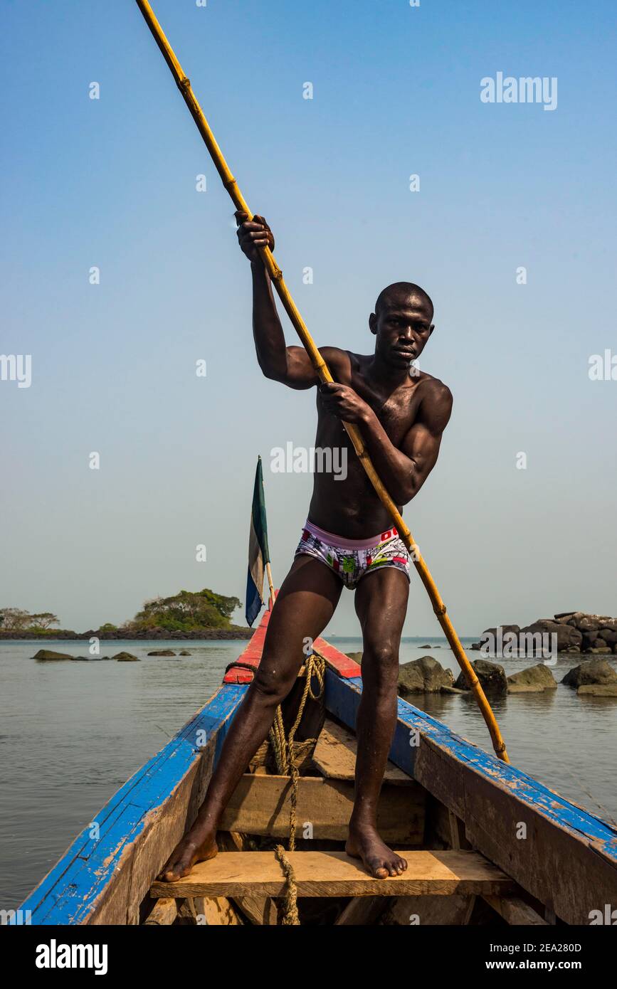 Homme poussant son petit bateau sur les îles Banana, Sierra Leone Banque D'Images