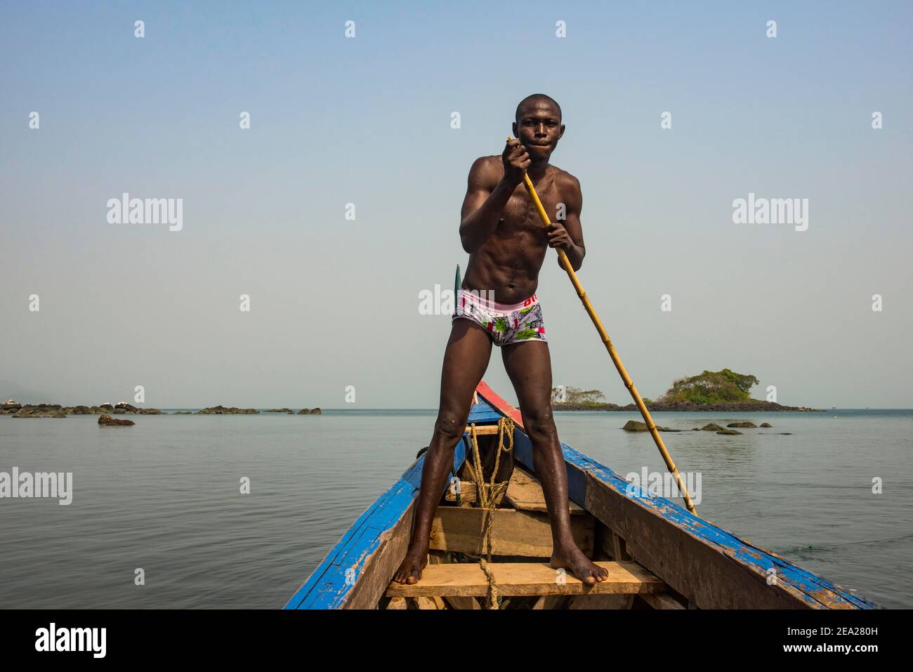 Homme poussant son petit bateau sur les îles Banana, Sierra Leone Banque D'Images