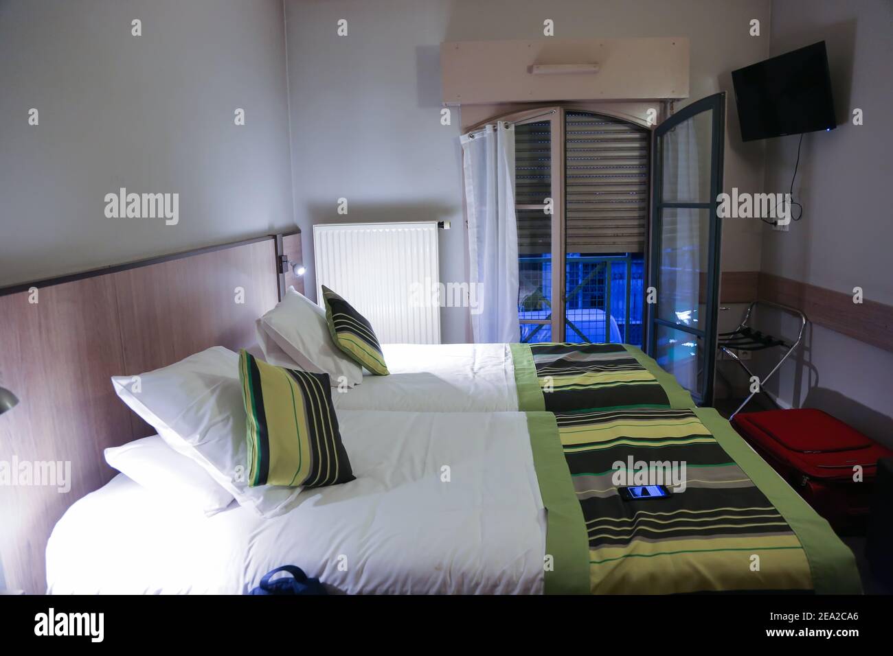L'intérieur de la chambre est dans un hôtel bon marché à Lyon en France dans la soirée. Deux lits sont à l'avant-plan et les stores à l'étage sont contre l'arrière Banque D'Images
