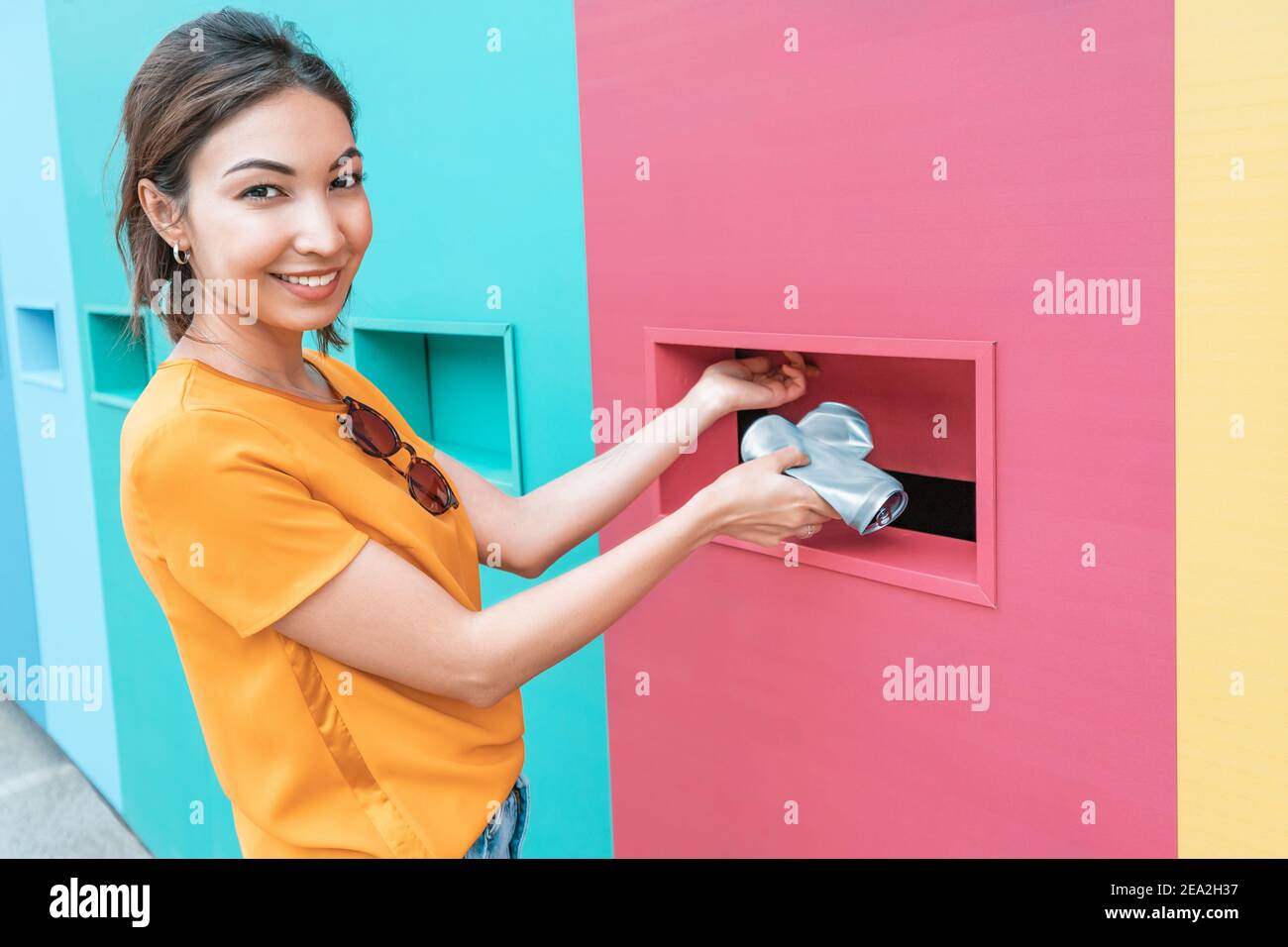 Une femme asiatique passe la canette en aluminium au point de réception pour les ordures et les déchets triés. Éducation et protection de l'environnement Banque D'Images