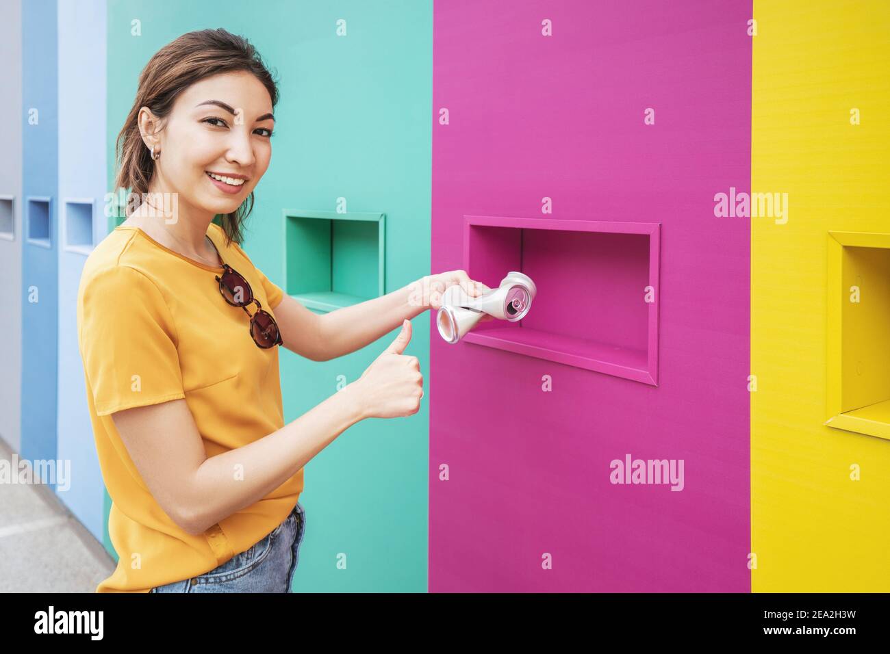 Une femme asiatique passe la canette en aluminium au point de réception pour les ordures et les déchets triés. Éducation et protection de l'environnement Banque D'Images