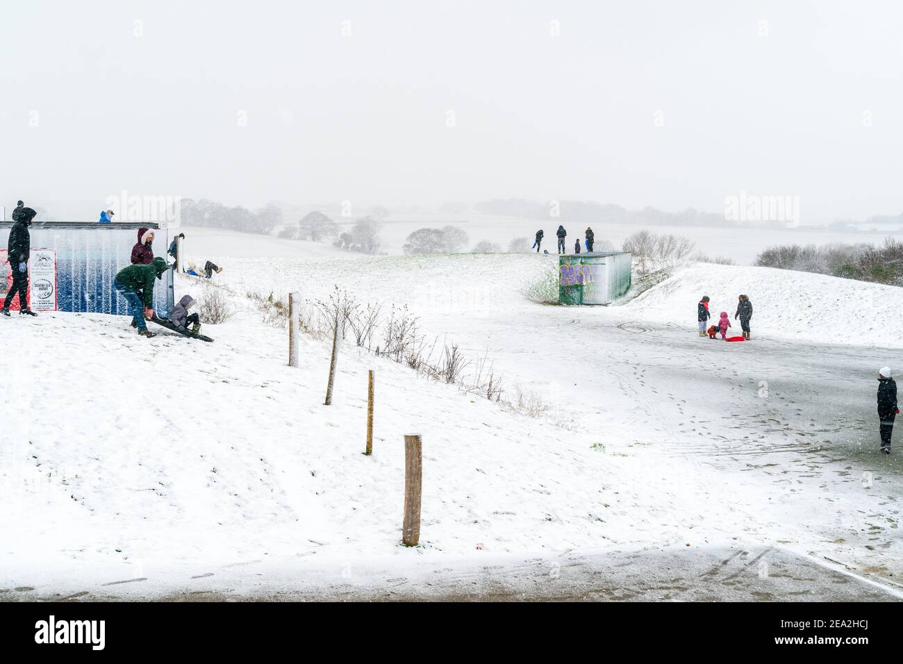 Les gens et les familles dans la neige pendant la Bête de février 2021 de la tempête de neige est-2. La neige couvrait une petite colline avec des gens qui utilisaient des traîneaux pour descendre la colline. Le fond est recouvert de neige et d'arbres. Banque D'Images