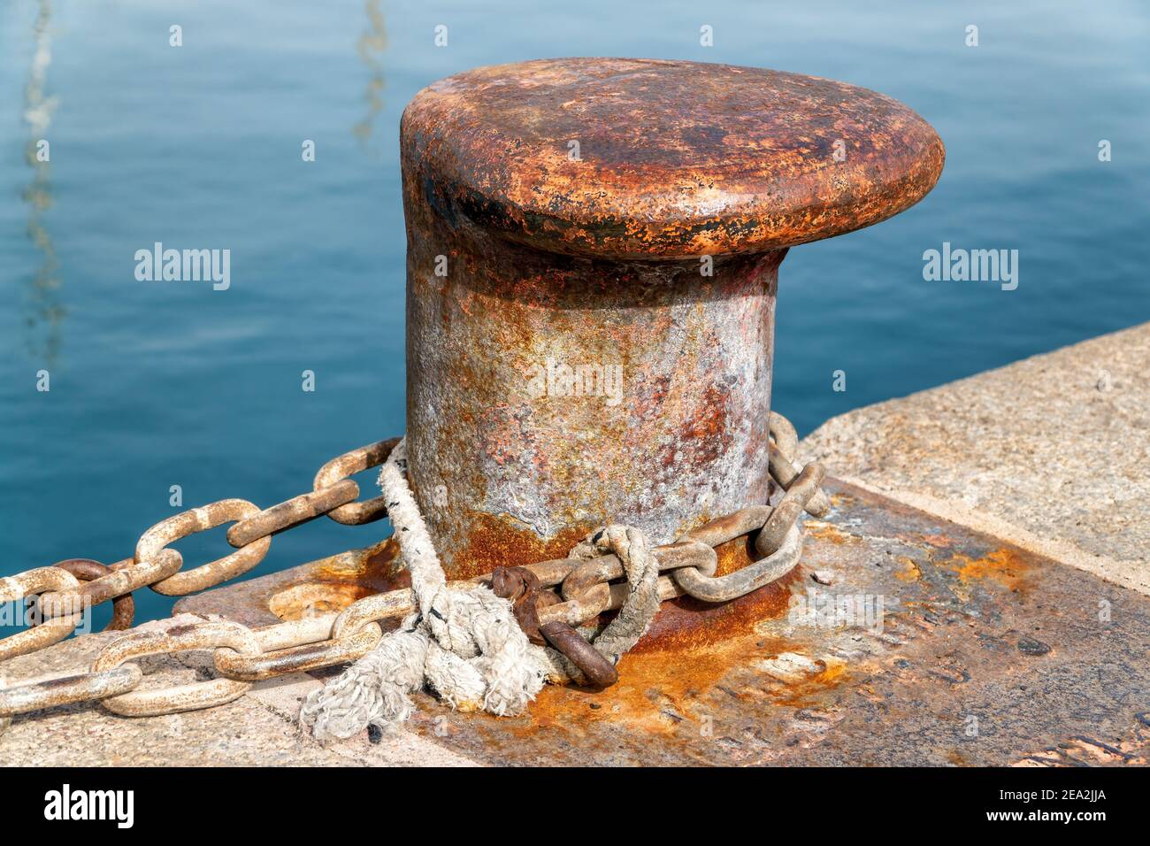 Un vieux bollard marin rouillé avec des cordes nautiques le long du quai. Banque D'Images