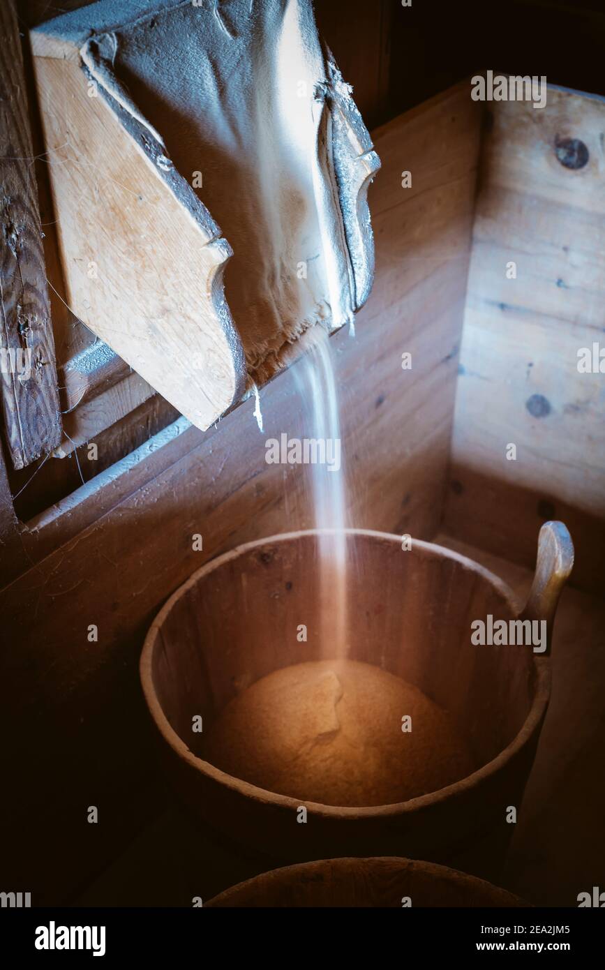 La farine s'infiltre du moulin à bois dans un seau à l'intérieur du moulin à farine historique dans la vallée du moulin de Cammill, Tyrol du Sud, Italie Banque D'Images