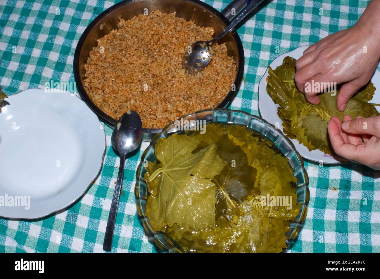 La femme enveloppe des feuilles de raisin pour le Sarma turc ou le Dolma (Yaprak Sarma). Cuisine turque traditionnelle. Concept de cuisine maison. Banque D'Images