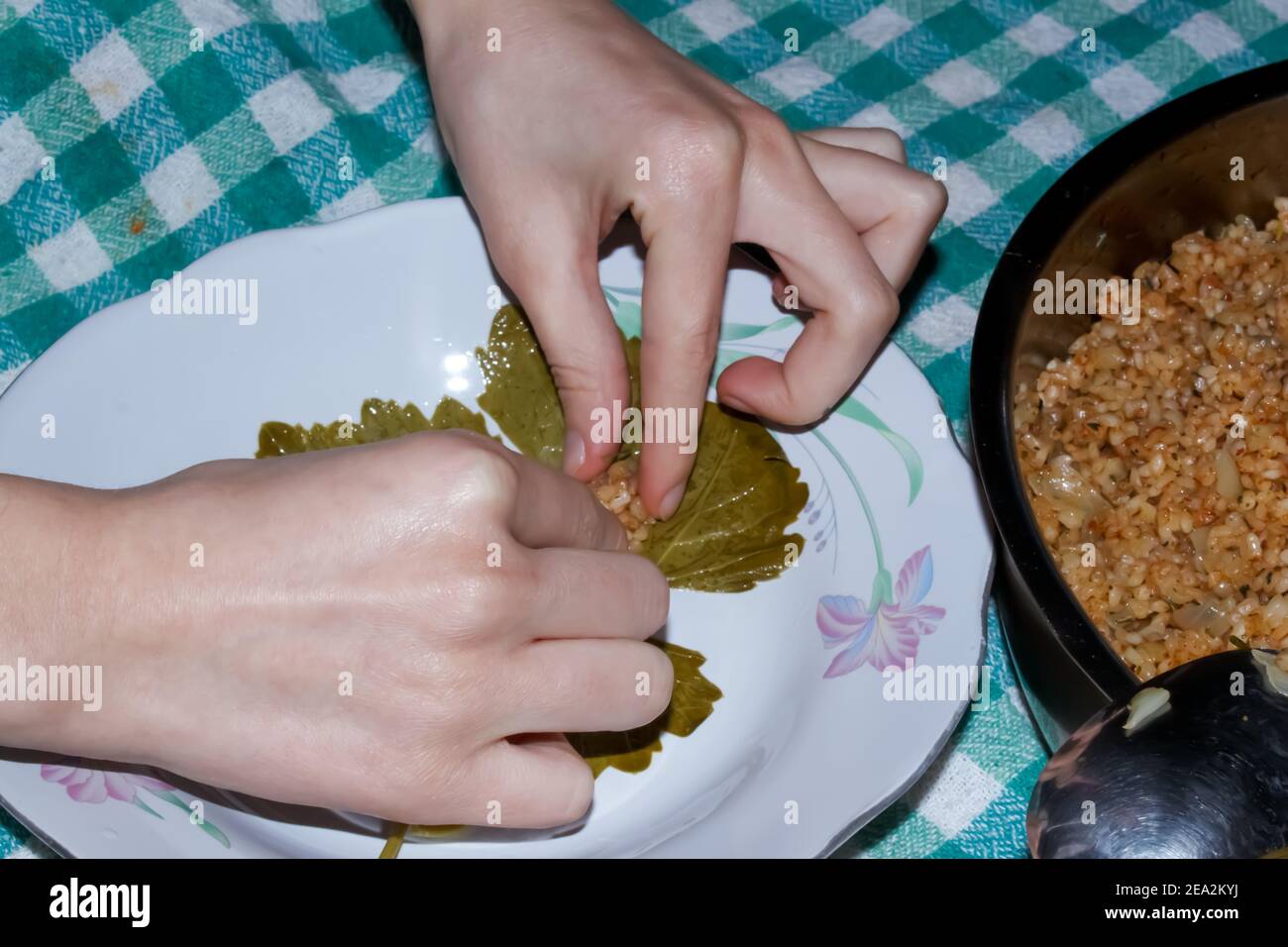 La femme enveloppe des feuilles de raisin pour le Sarma turc ou le Dolma (Yaprak Sarma). Cuisine turque traditionnelle. Concept de cuisine maison. Banque D'Images