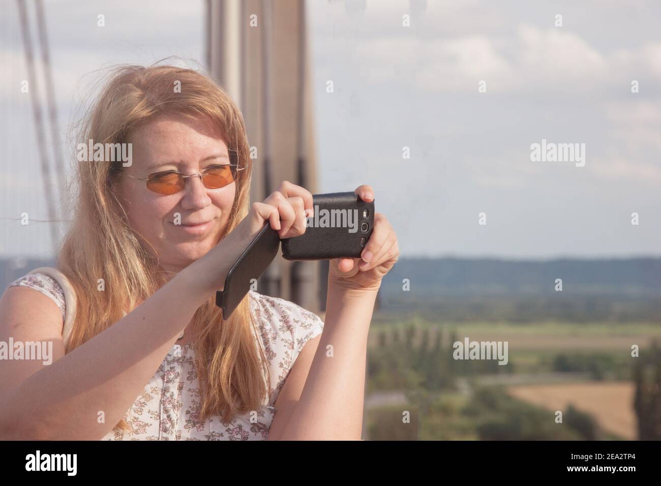 Belle femme blonde touriste prend des photos sur le paysage de pont en france. Femme tenant un téléphone portable. Banque D'Images