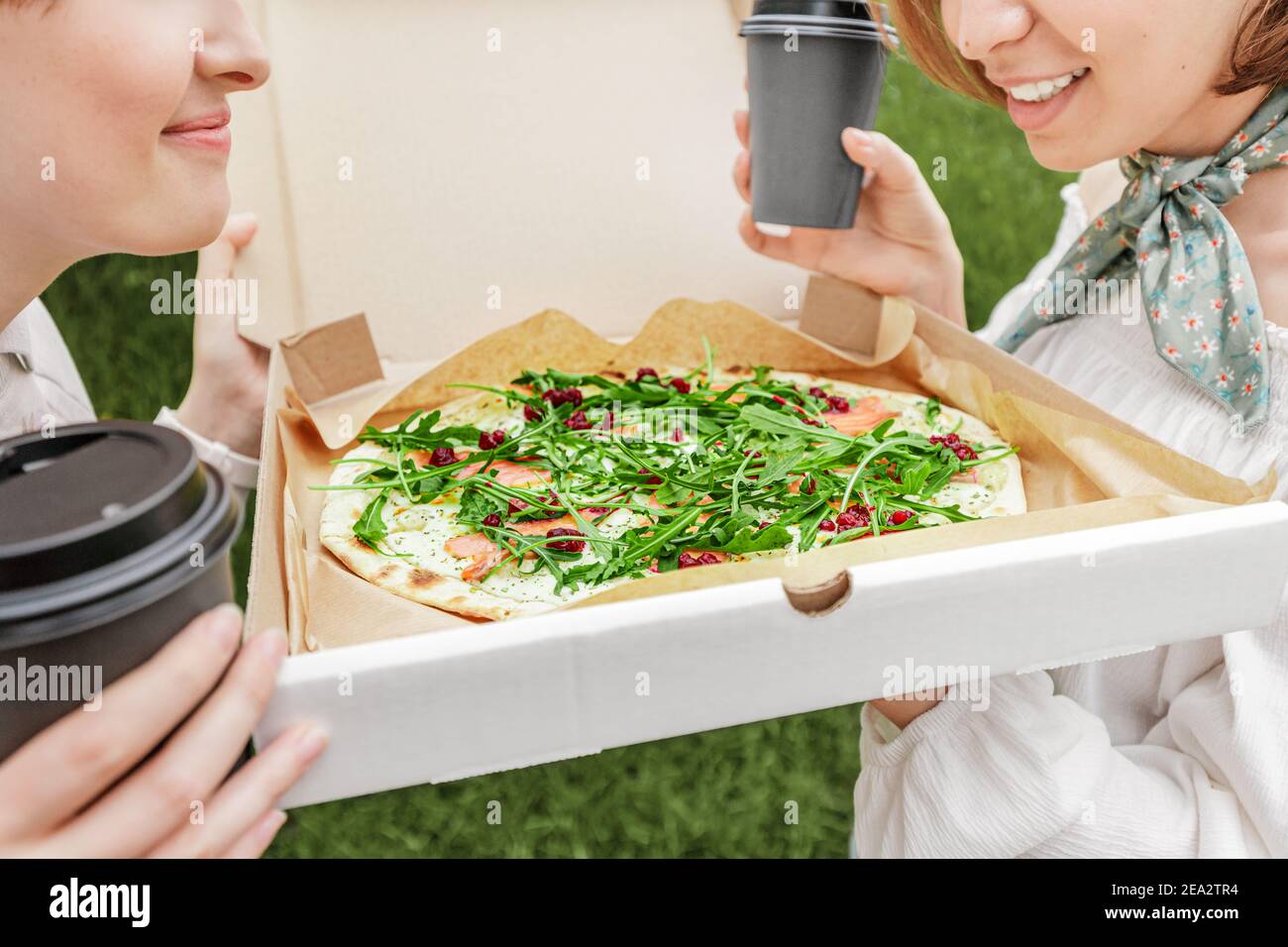 Les amies partagent une pizza à emporter. Ils mangent de délicieux fast food et de boire du café et de socialiser dans une place confortable de la ville Banque D'Images
