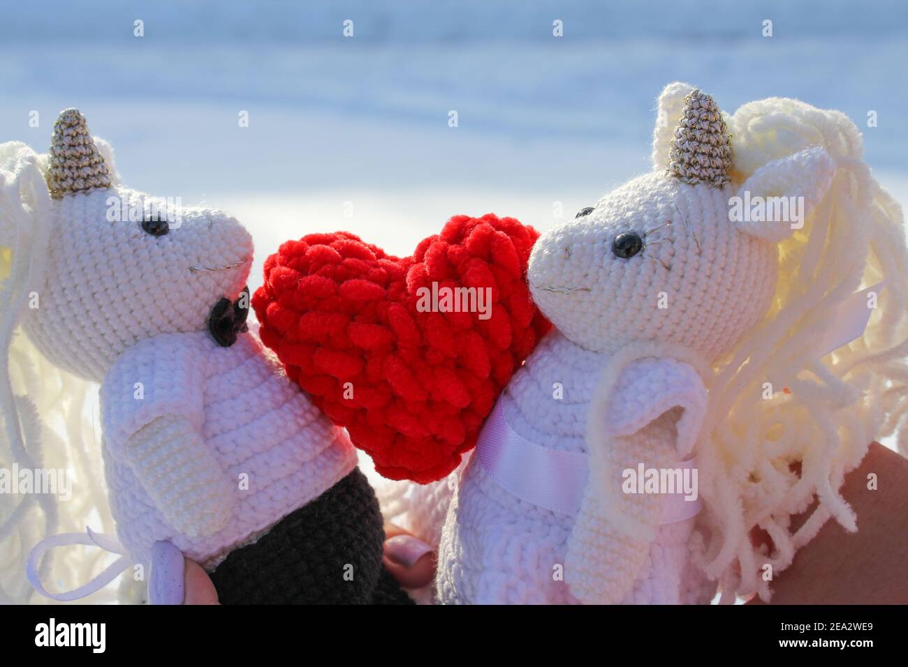 Jouets en crochet licornes en costumes de mariage avec un coeur rouge, histoire d'amour Banque D'Images