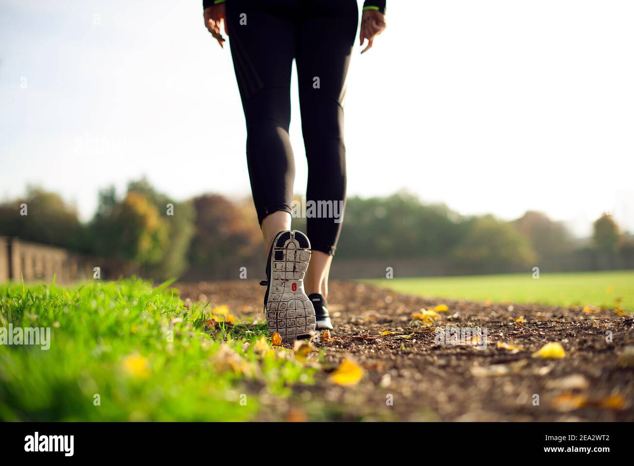 Vue à angle bas de la femme sportive marchant sur la piste dans le champ vert, gros plan des jambes, de l'arrière. Concept de style de vie actif en extérieur. Londres, Royaume-Uni Banque D'Images