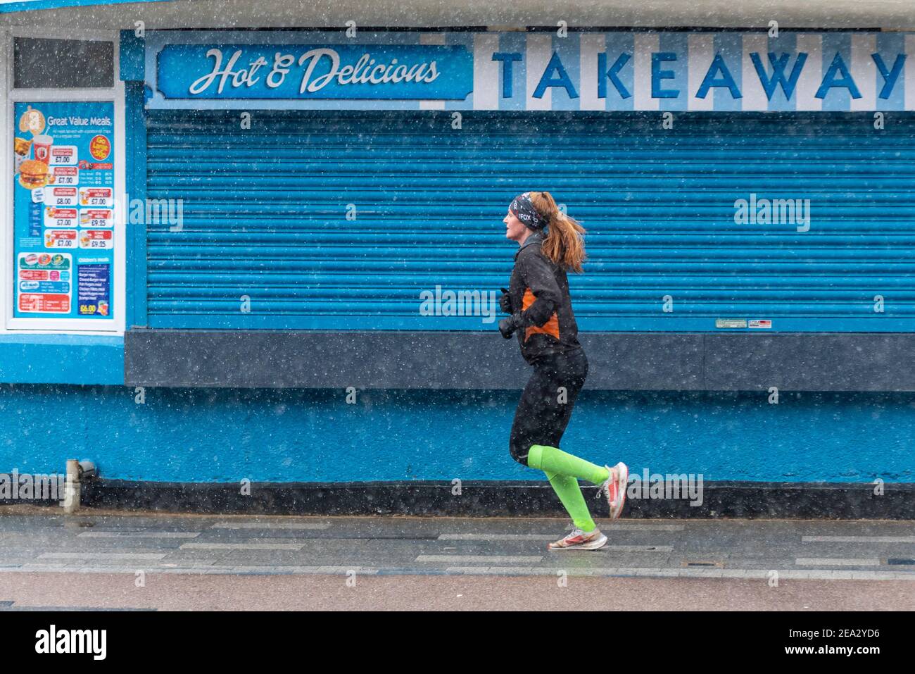 Jogging féminin en bord de mer fermé à emporter sur Southend sur le front de mer tandis que Storm Darcy s'approche de la chute de luge. Neige Banque D'Images