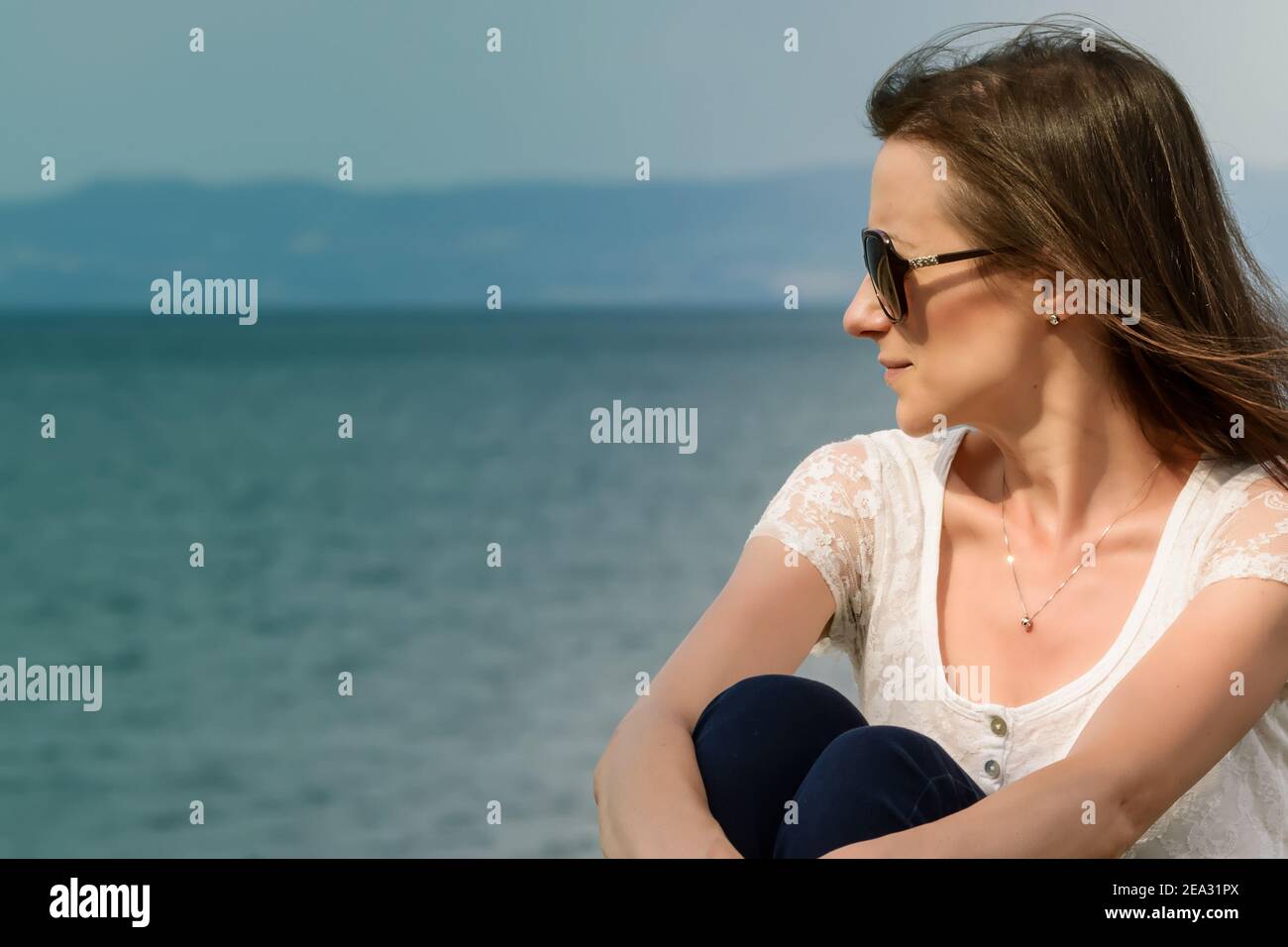 Jeune femme caucasienne avec de grandes lunettes de soleil regardant loin par le lac de Bolsena Banque D'Images