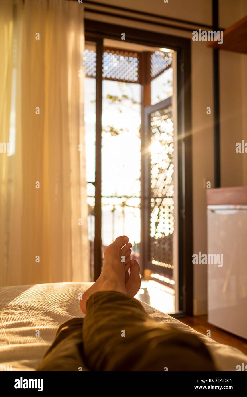 couché et détente dans le lit face à une fenêtre au coucher du soleil Photo  Stock - Alamy