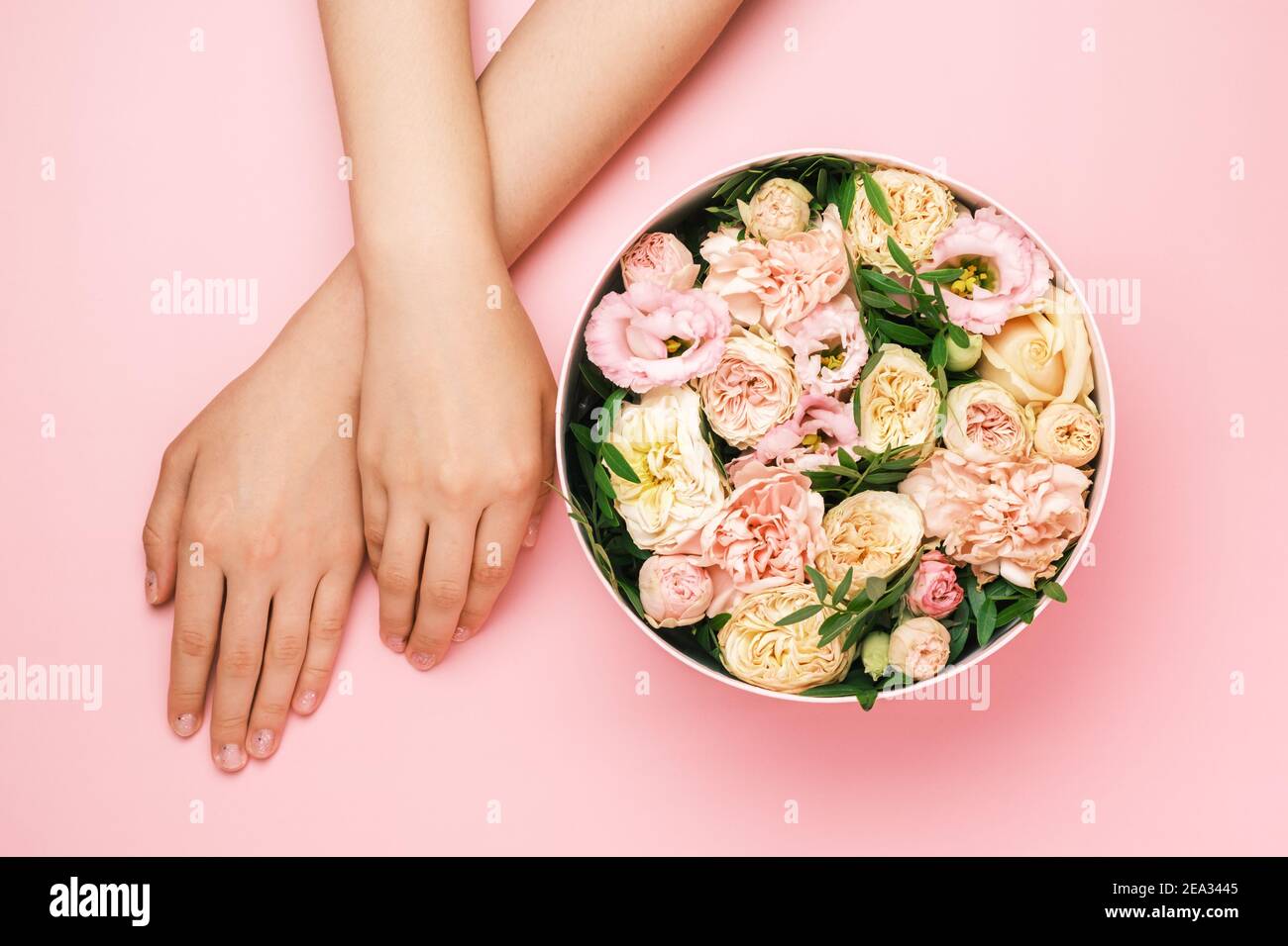 Boîte avec de belles fleurs à côté des mains de womans sur le fond noir avec espace de copie. Concept de carte salone beauté. Cadeau pour le 8 mars, Fête des mères Banque D'Images