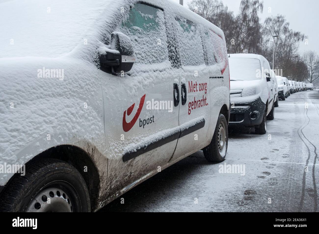 Pare-brise / pare-vent et vitres de voiture des véhicules de livraison Belge Bpost garés couverts de neige par temps froid en hiver, Belgique Banque D'Images