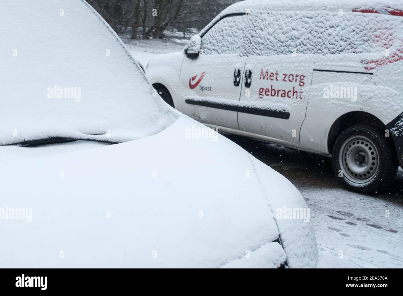 Pare-brise / pare-vent et vitres de voiture des véhicules de livraison Belge Bpost garés couverts de neige par temps froid en hiver, Belgique Banque D'Images