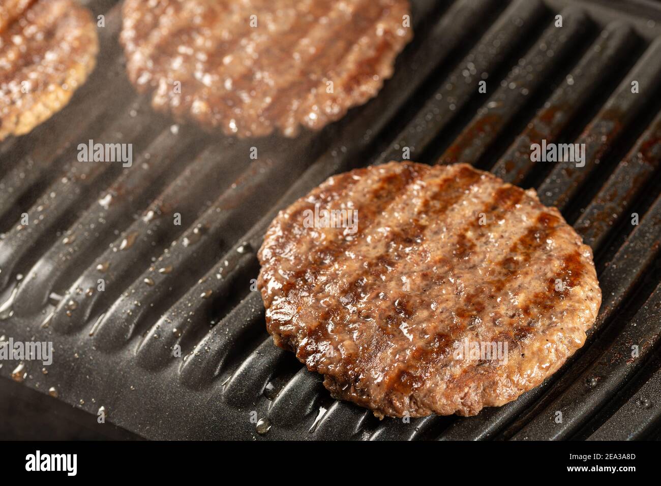 Côtelettes de bœuf frais sur un gril. Cuisiner un hamburger à la maison. Concept de nourriture délicieuse et saine Banque D'Images