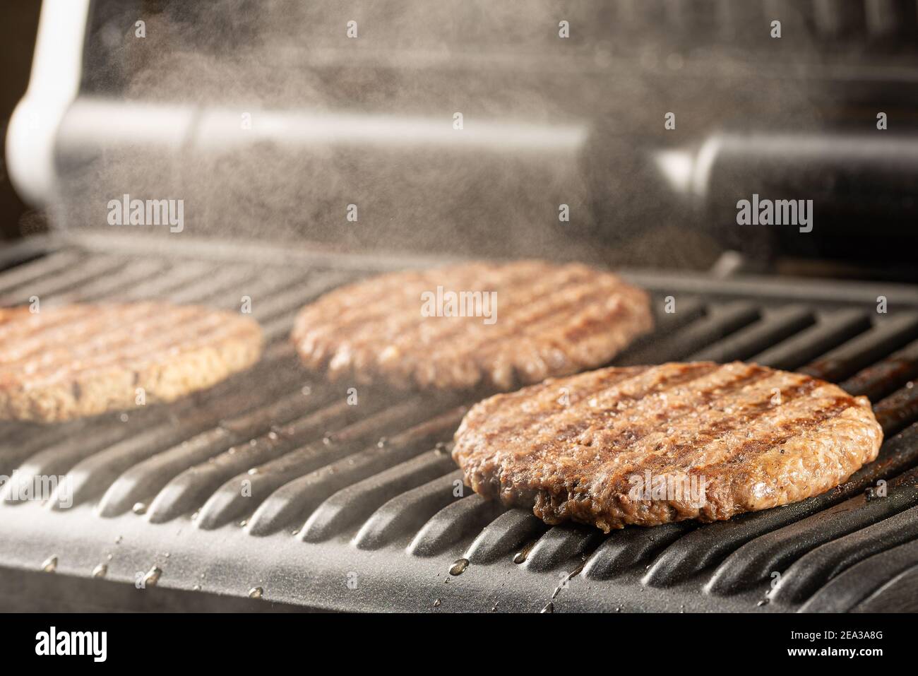 Côtelettes de bœuf juteuses et fraîches sur un gril. Cuisiner un hamburger à la maison. Concept de nourriture délicieuse et saine Banque D'Images