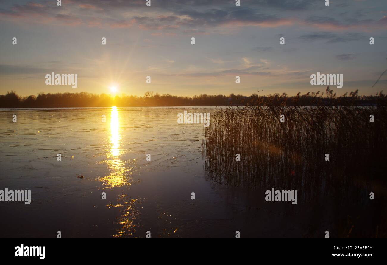 Coucher de soleil d'hiver avec reflet de la lumière du soleil sur la glace sur le lac gelé Banque D'Images