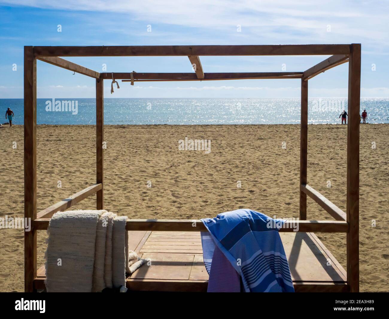 Lit de plage en bois sans touristes sur une plage à Marbella, un jour d'automne ensoleillé. Banque D'Images