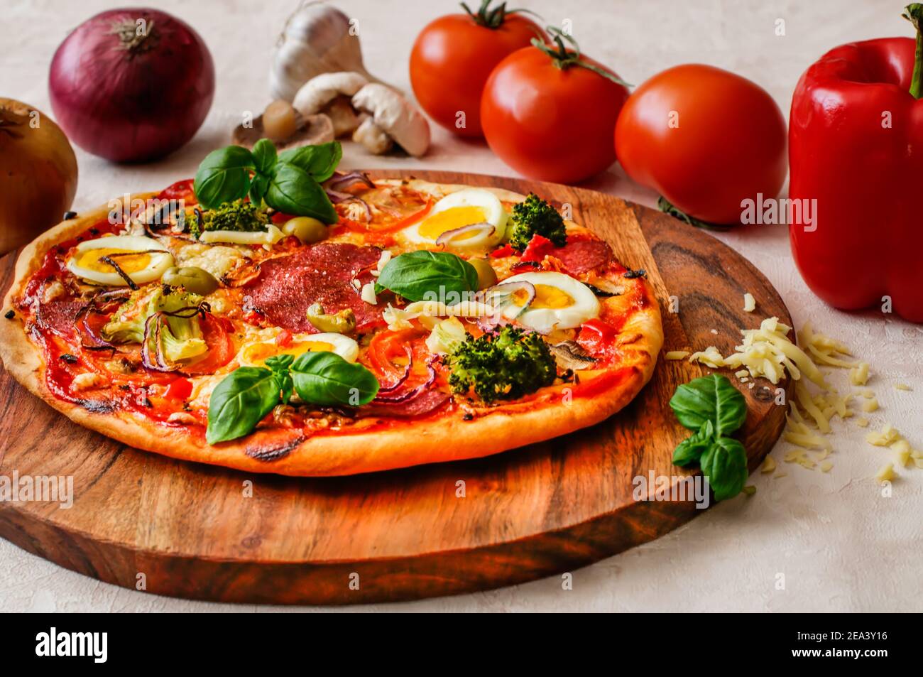 Pizza maison avec salami, fromage, œuf et légumes, garnie de basilic Banque D'Images