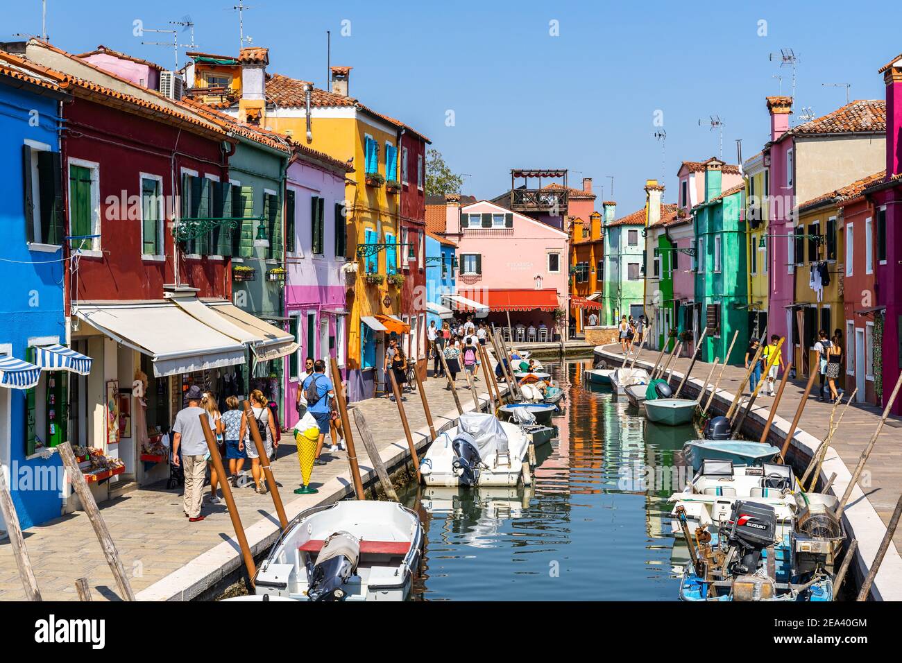 Burano, Italie, 2020 septembre – les touristes se baladent le long d'un canal typique de Burano avec des maisons colorées et une boutique de cadeaux Banque D'Images