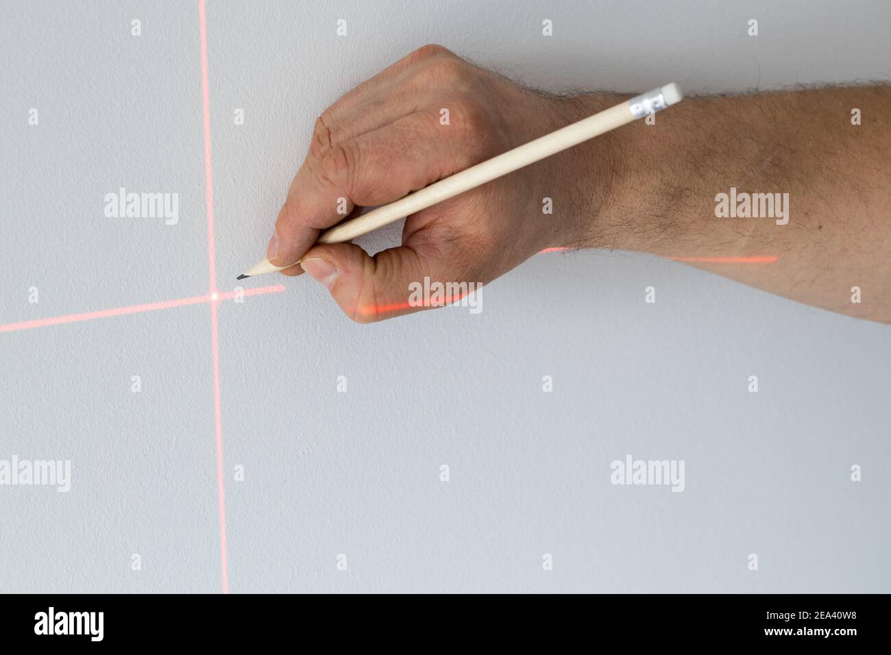 Un spécialiste marque un point sur un mur avec un laser électronique Banque D'Images