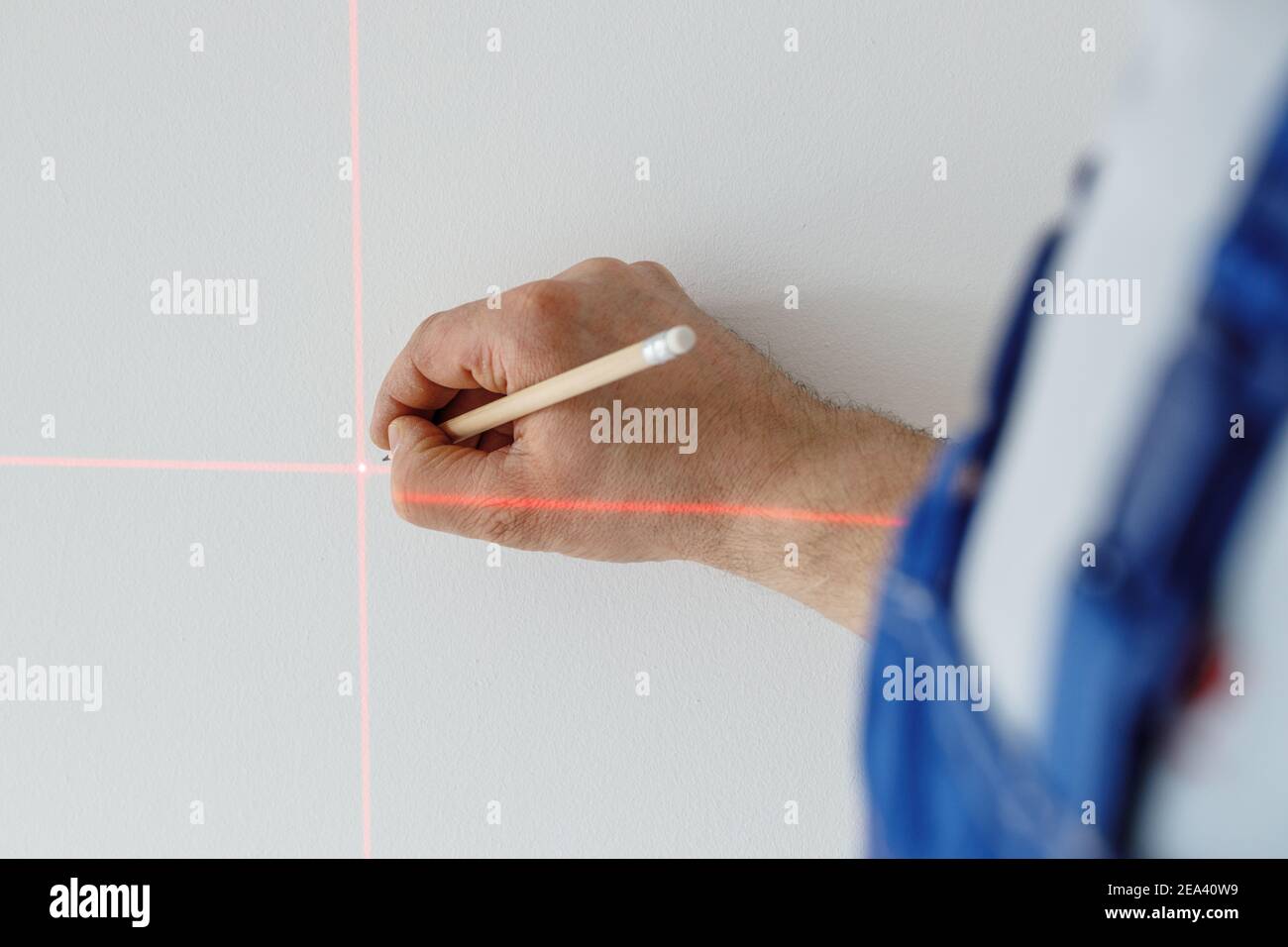 Un spécialiste marque un point sur un mur avec un laser électronique Banque D'Images