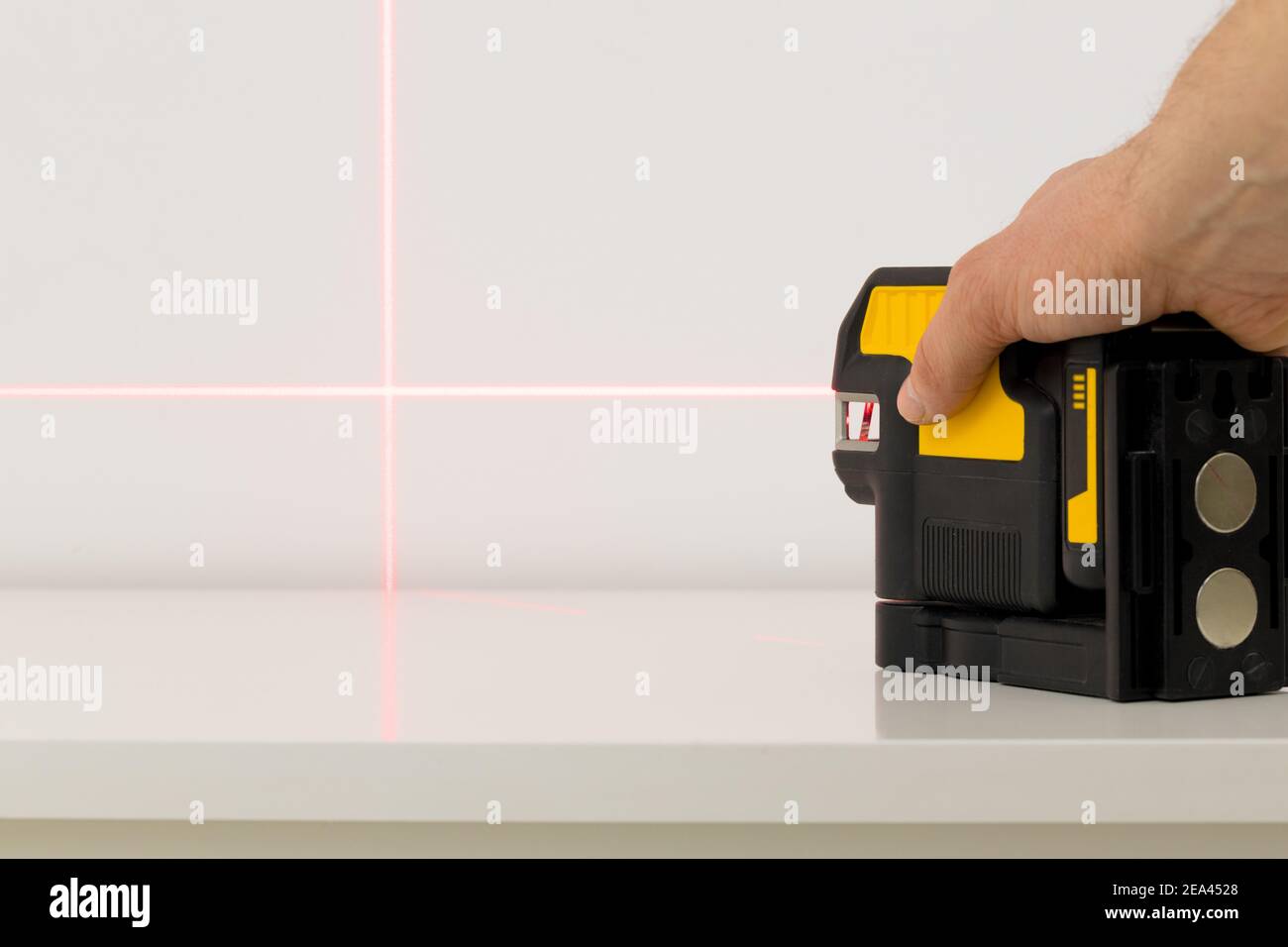 le spécialiste utilise un laser électronique pour vérifier les angles droits et les lignes lors de la prise de mesures de la pièce Banque D'Images
