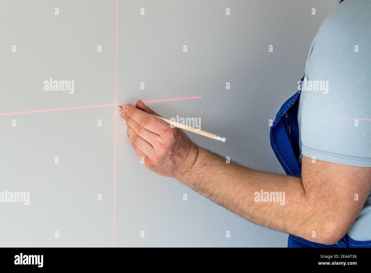 Un spécialiste marque un point sur un mur avec un laser électronique Banque D'Images