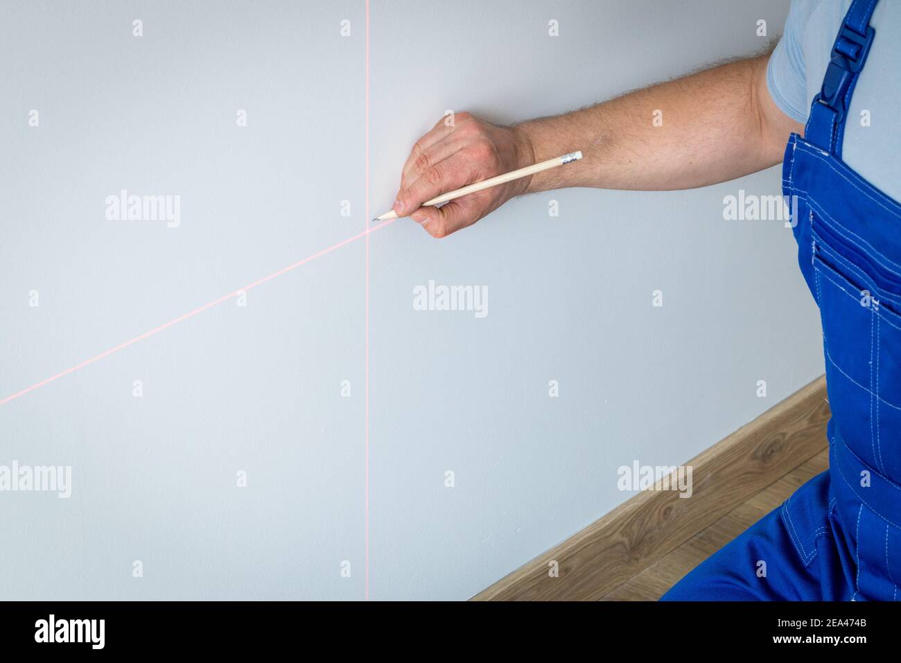 Un spécialiste marque un point sur un mur avec un laser électronique Banque D'Images