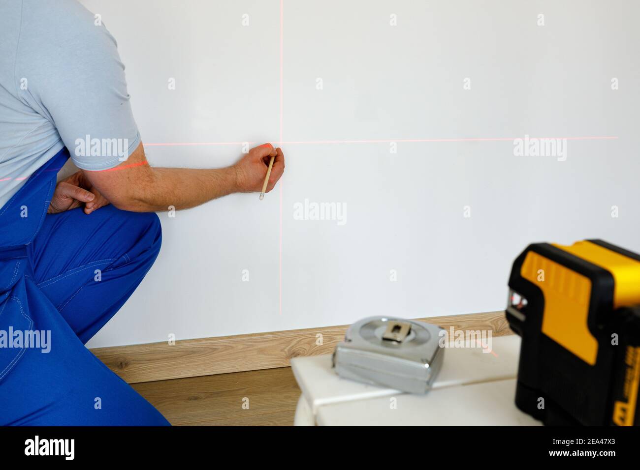 Un spécialiste marque des points sur un mur avec un électronique laser pour l'indication des niveaux et des traits d'aplomb Banque D'Images