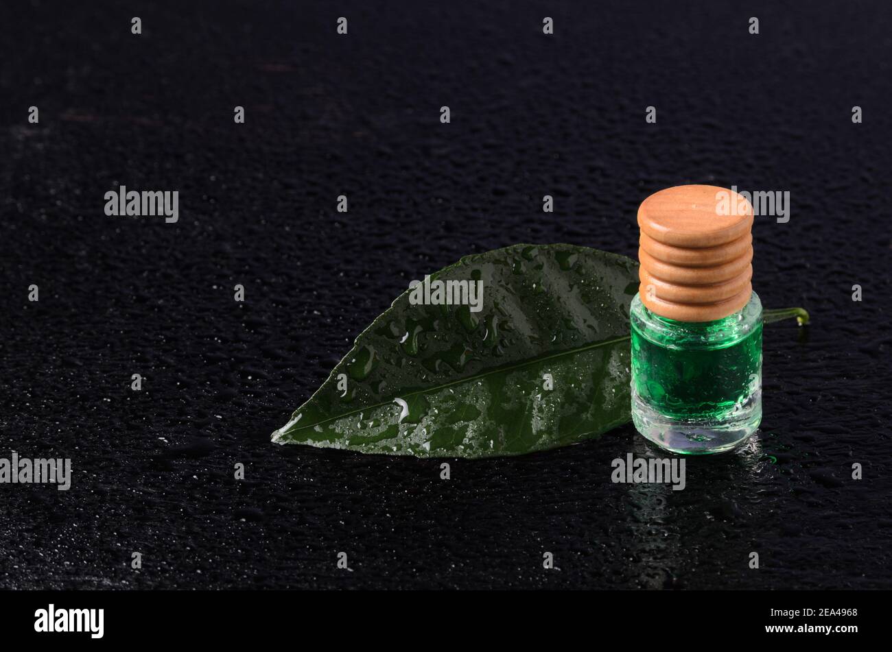 Saveur de citron de couleur émeraude dans une bouteille en verre avec un bouchon en bois sur une feuille verte avec des gouttes d'eau. La touche Dark. Banque D'Images