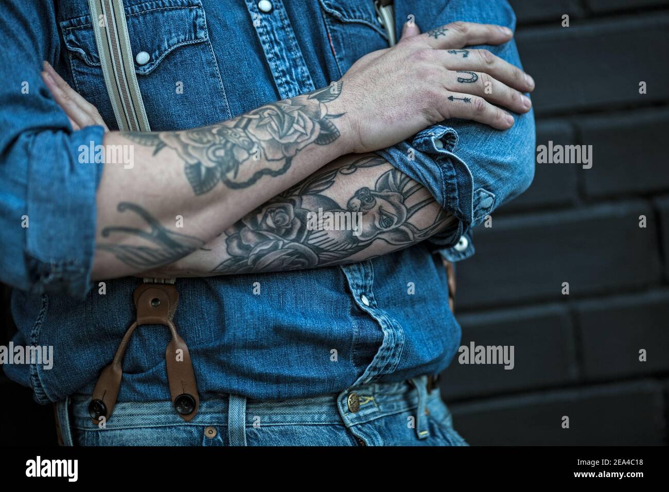 homme avec tatouages portant un jean avec bretelles Banque D'Images