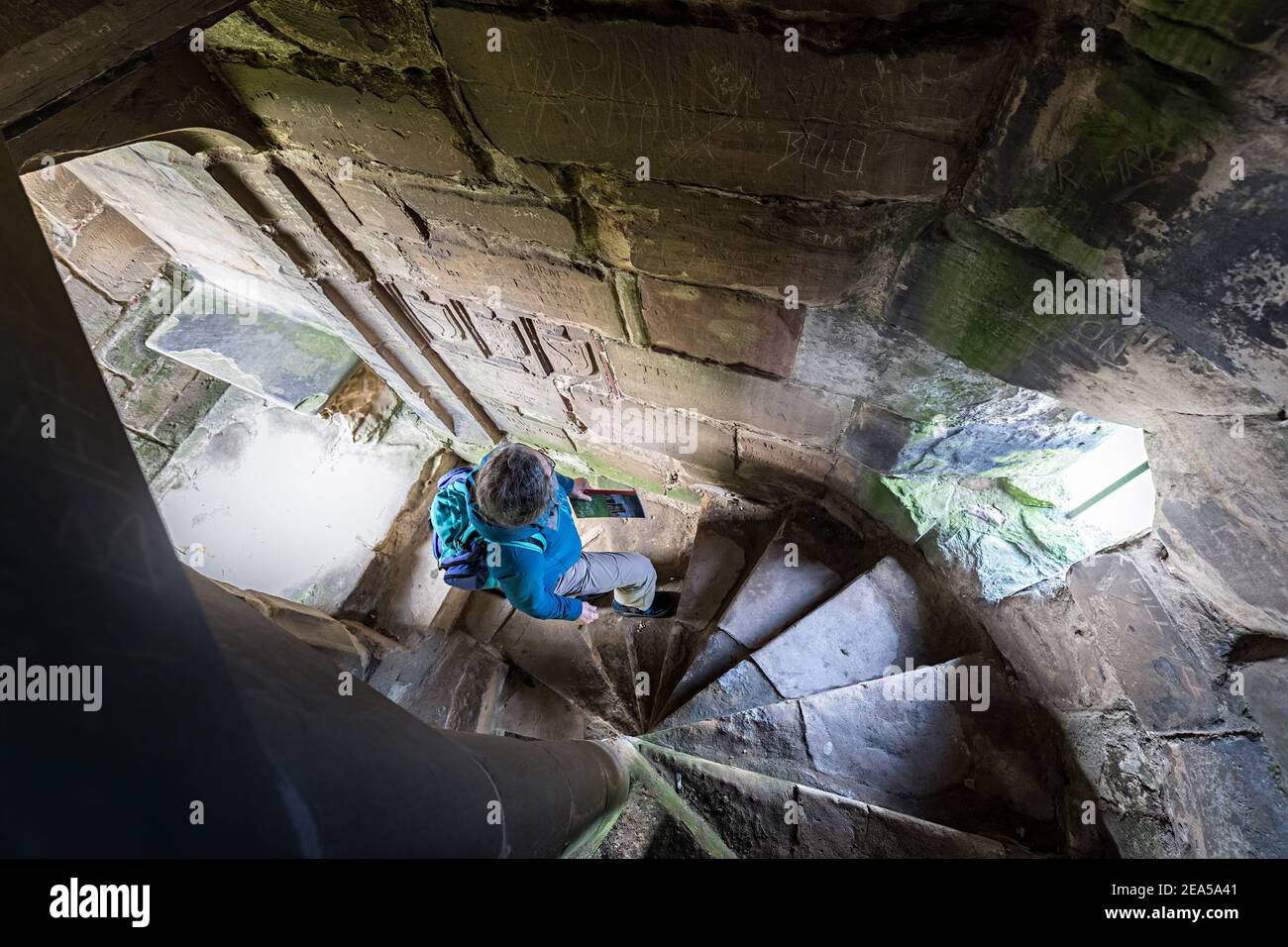 Touriste regardant les vieux graffiti dans l'escalier en colimaçon, Ashby de la Zouch Castle, Leicestershire, Angleterre, Royaume-Uni Banque D'Images