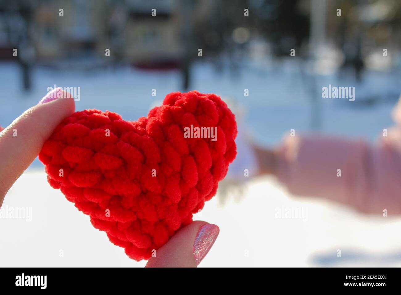 Symboles tricotés, coeur rouge dans les mains comme symbole de l'amour Banque D'Images