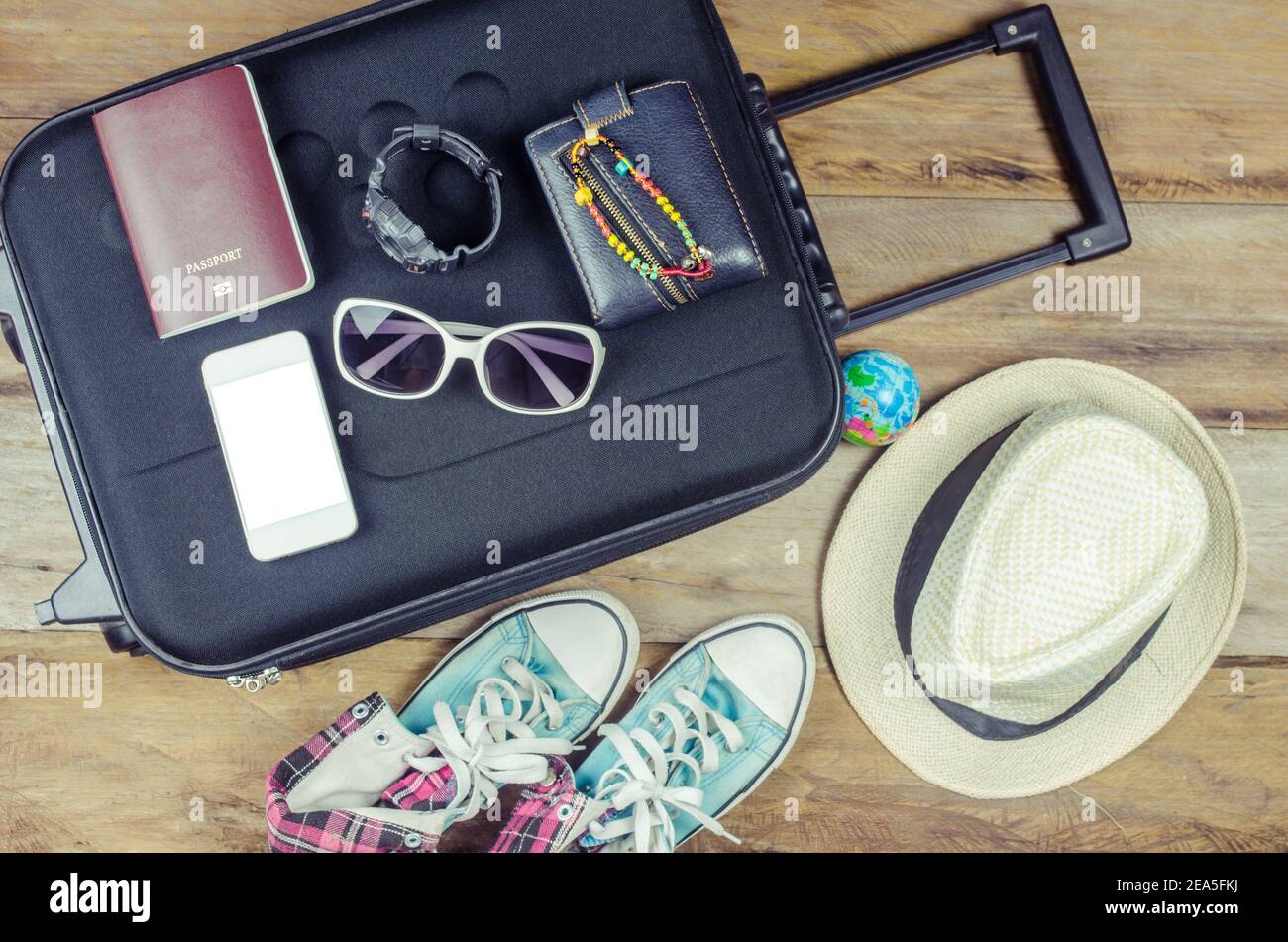 Passeport du voyageur de vêtements, portefeuille, lunettes, montres, appareils de smartphone, chapeau, chaussures, sur un plancher en bois sur les bagages prêts à voyager. Banque D'Images