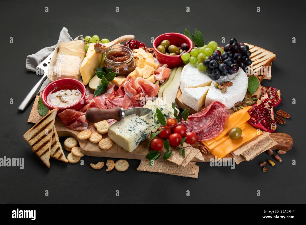 Table de hors-d'œuvre. Fromage, fuits et carton de viande sur fond sombre. Banque D'Images