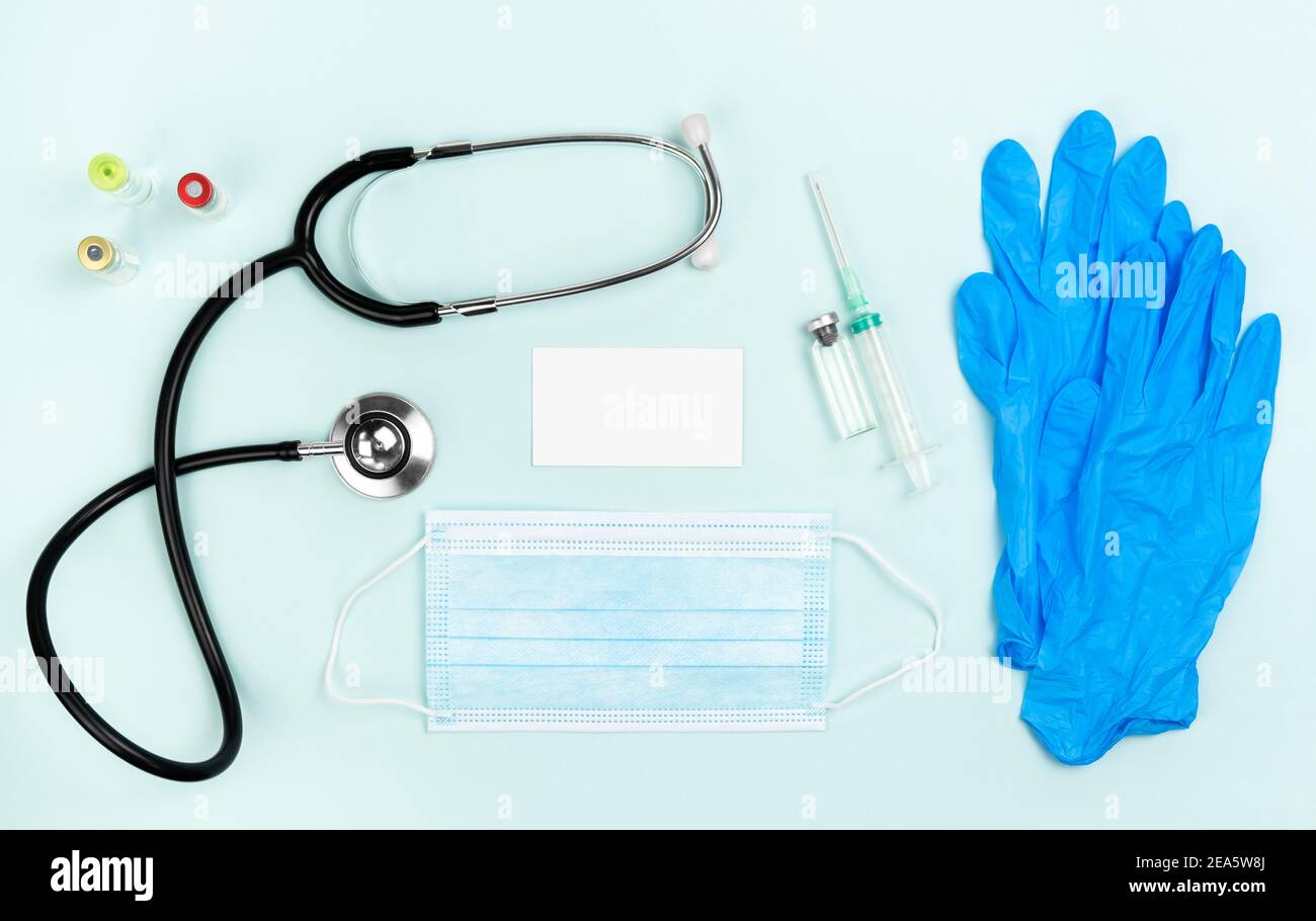 Flatlay médecin lieu de travail avec stéthoscope et avec masque et avec seringue et ampoules avec maquette de bloc-notes. Le concept de la vaccination, la vaccination, Banque D'Images