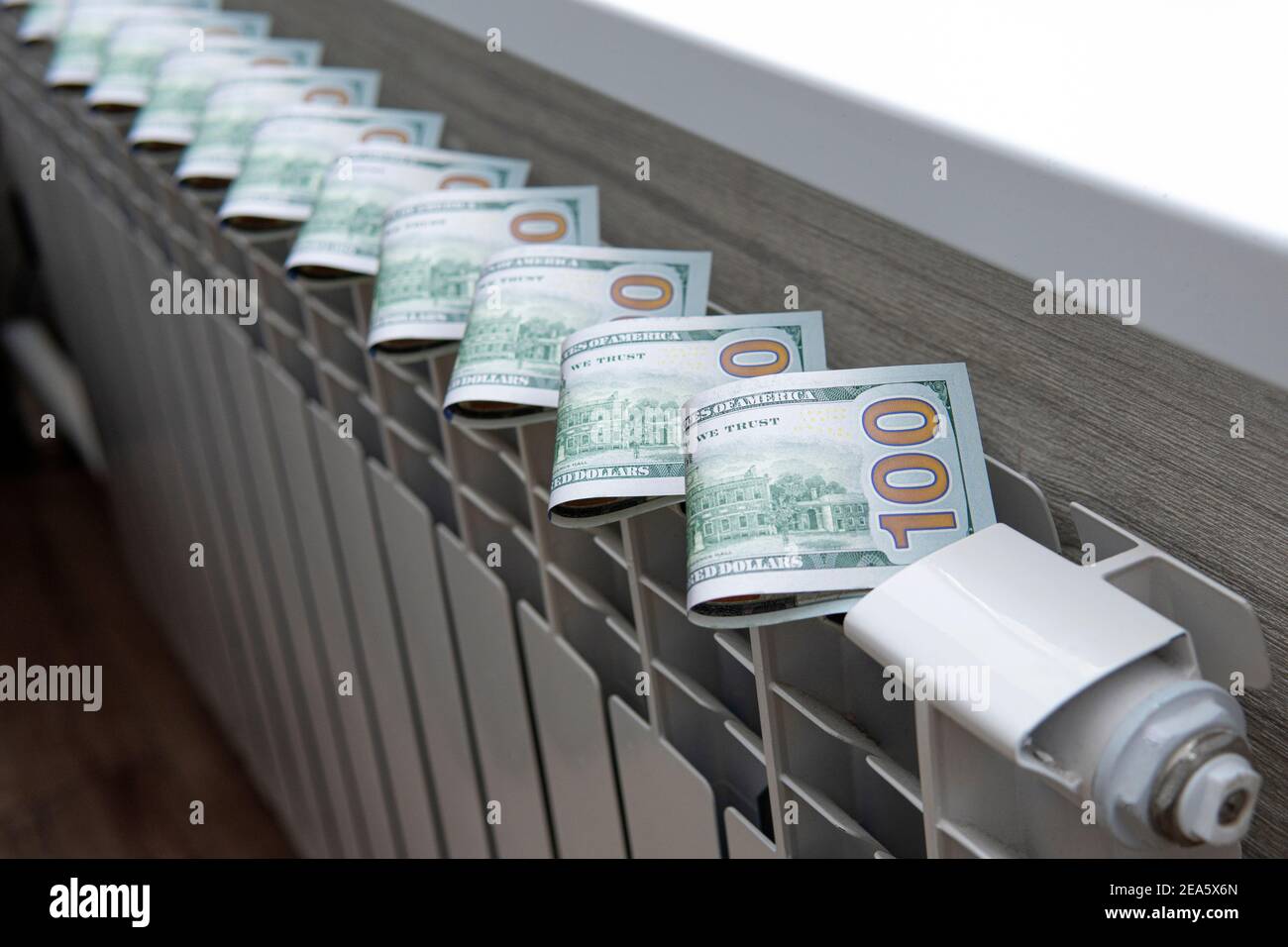 Le concept de payer pour le chauffage dans les maisons avec un climat froid. L'argent comptant est couché sur un radiateur en métal blanc près de la fenêtre. Banque D'Images