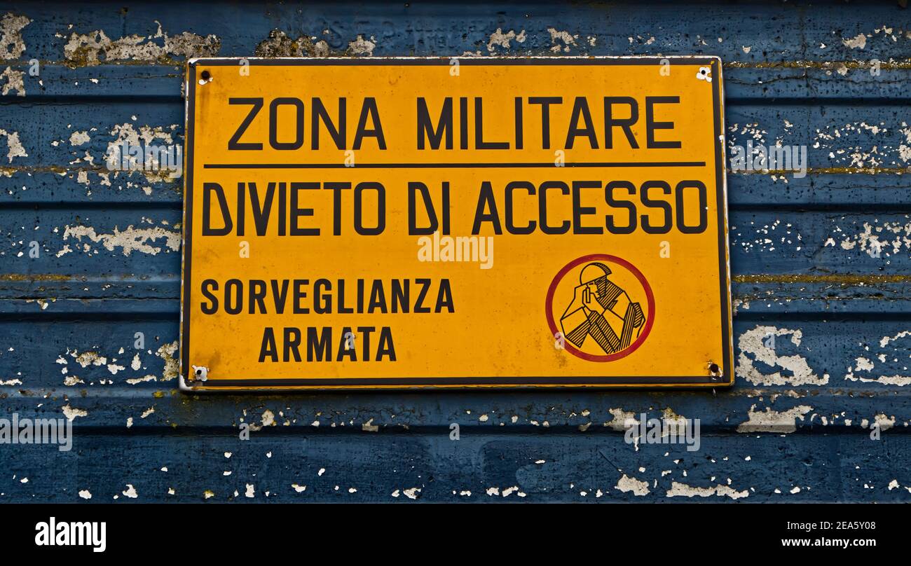 Zone militaire italienne avec panneau jaune: 'Military zone, no Entry, armé surveillance'. 'Zona militare, divieto di accesso, sorveglianza armata' Banque D'Images