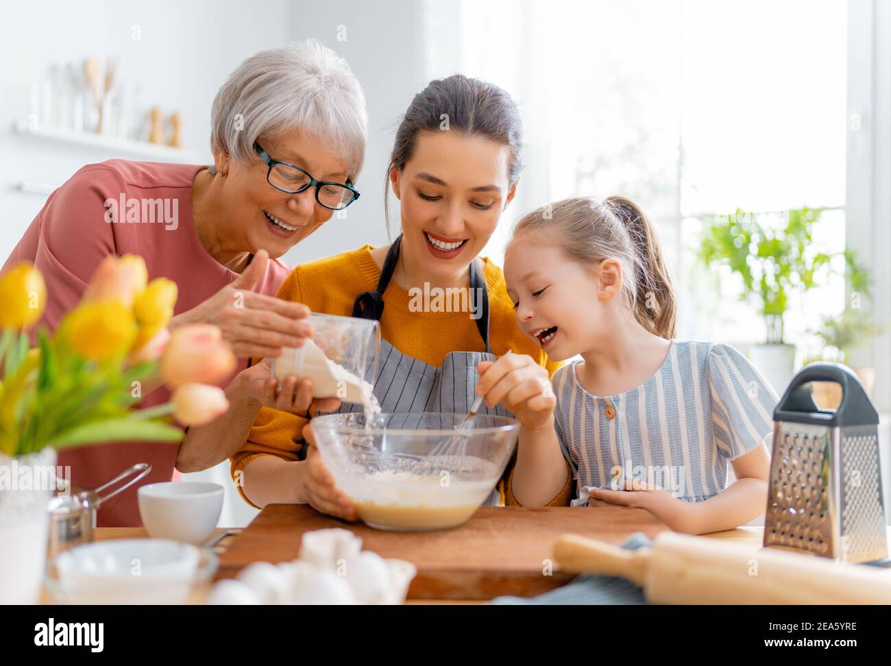 Une famille heureuse et aimante prépare la boulangerie ensemble. Granny, maman et enfant cuisent des biscuits et s'amusent dans la cuisine. Banque D'Images